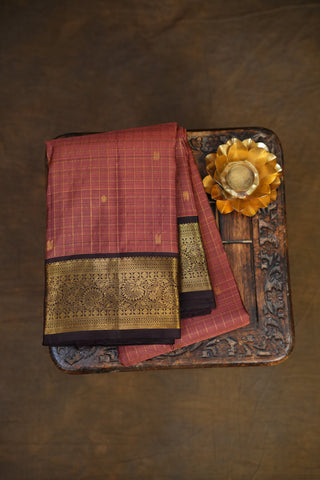 Copper saree with gold border on a wooden tray on a brown background