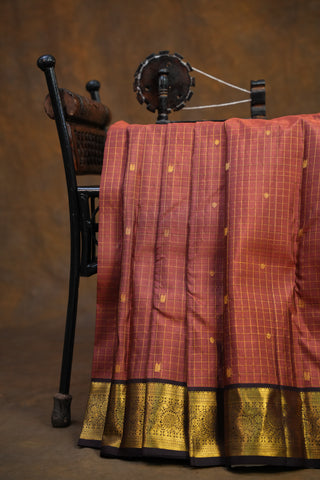 Red saree with gold border on a wooden hanger against a brown background