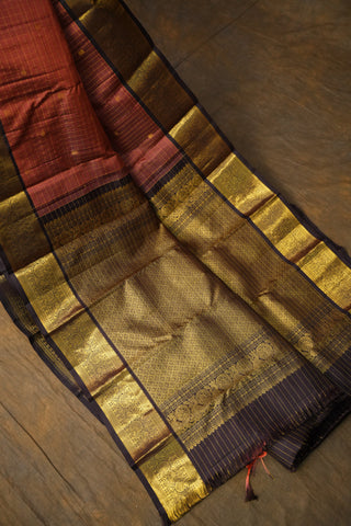 Folded traditional fabric with gold and red patterns on a wooden surface